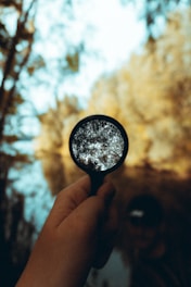 person holding magnifying glass during daytime