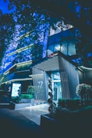 Modern condominium entrance with lush landscaping and elegant lighting at dusk.