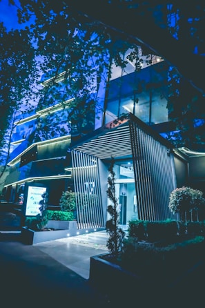 Modern condominium entrance with lush landscaping and elegant lighting at dusk.