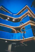 Close-up of a sleek glass building reflecting neon blue lights at dusk.