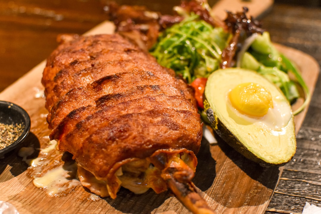 grilled meat with sliced lemon and green vegetable on brown wooden chopping board