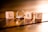 Four wooden blocks each displaying letters and numbers, arranged to spell the word 'LOVE'. A silver ring is intertwined with the letter 'O'. The scene is warmly lit, casting soft shadows on a wooden surface.