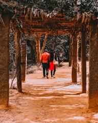 Bride walking down a tree-lined path with sunlight filtering through leaves.
