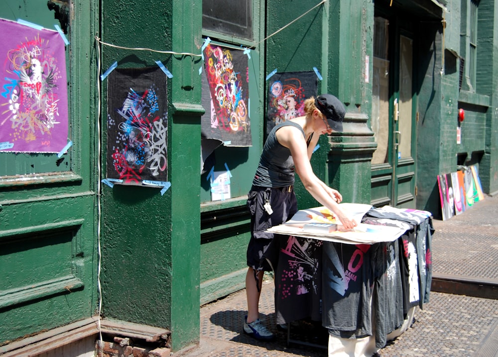 Mujer con camiseta negra sin mangas de pie junto a la puerta de madera verde