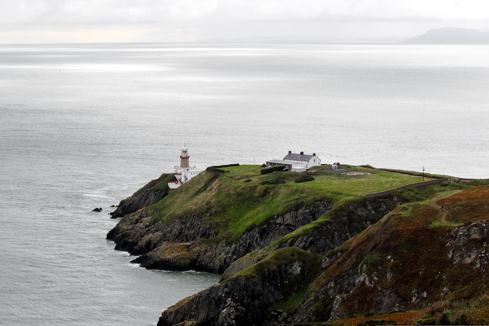 white lighthouse on green grass field near body of water during daytime