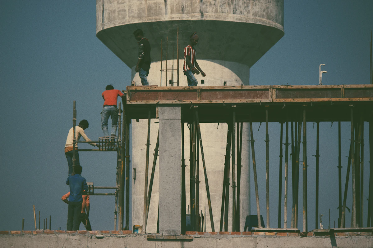 Workers building a reinforced concrete water tank structure at an Indian construction site