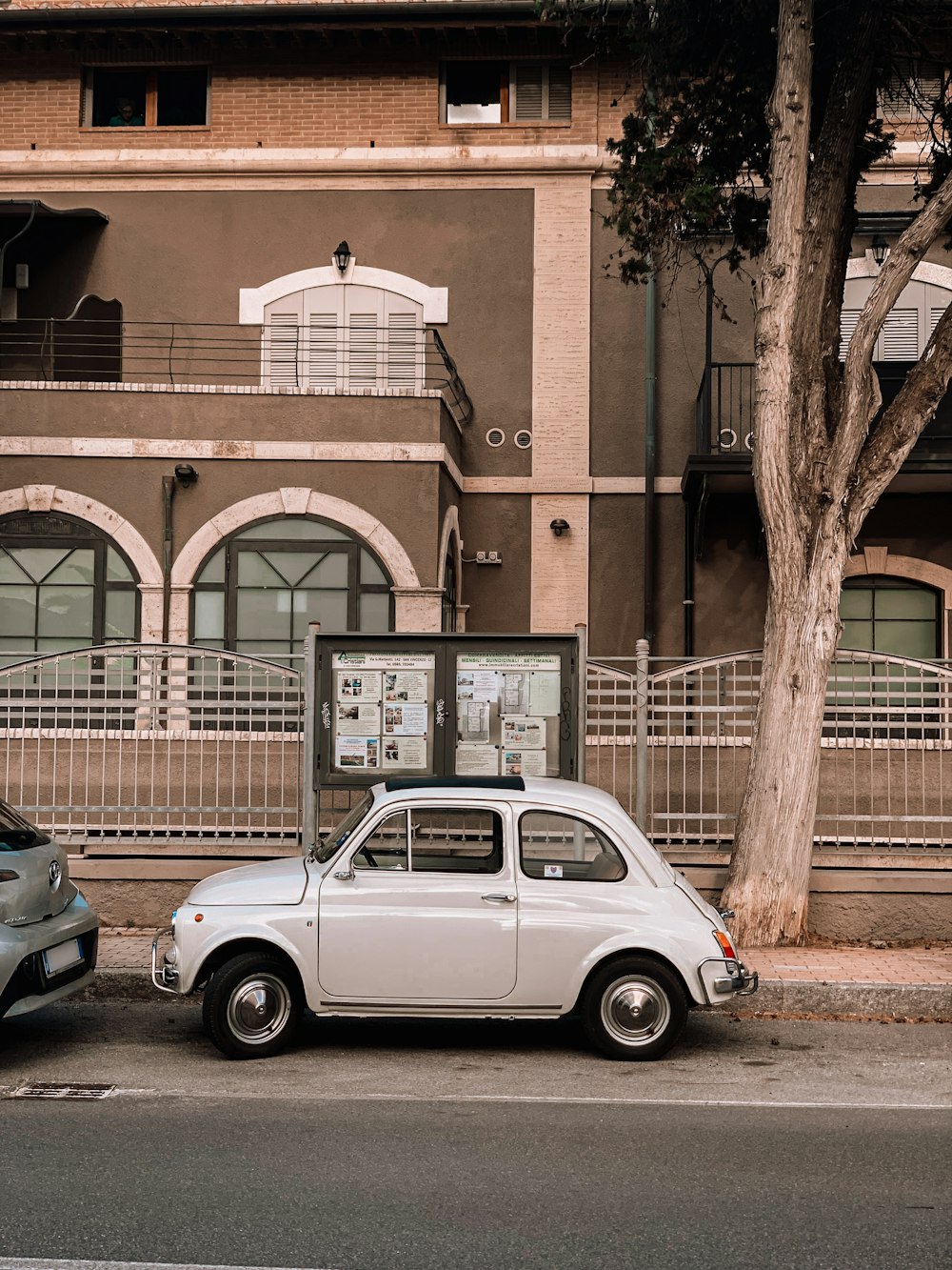 white sedan parked beside brown brick building