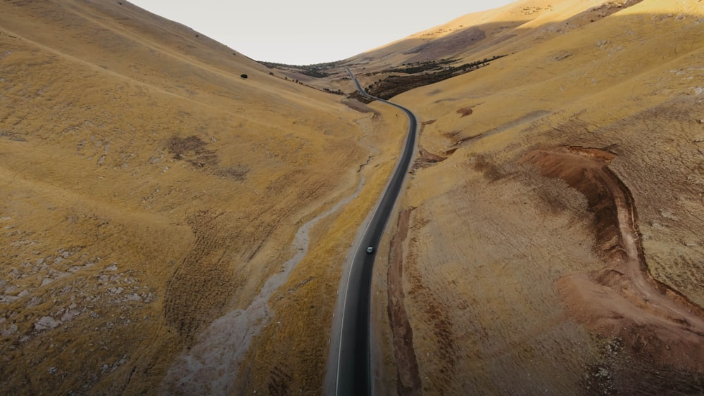 black asphalt road in the middle of brown sand