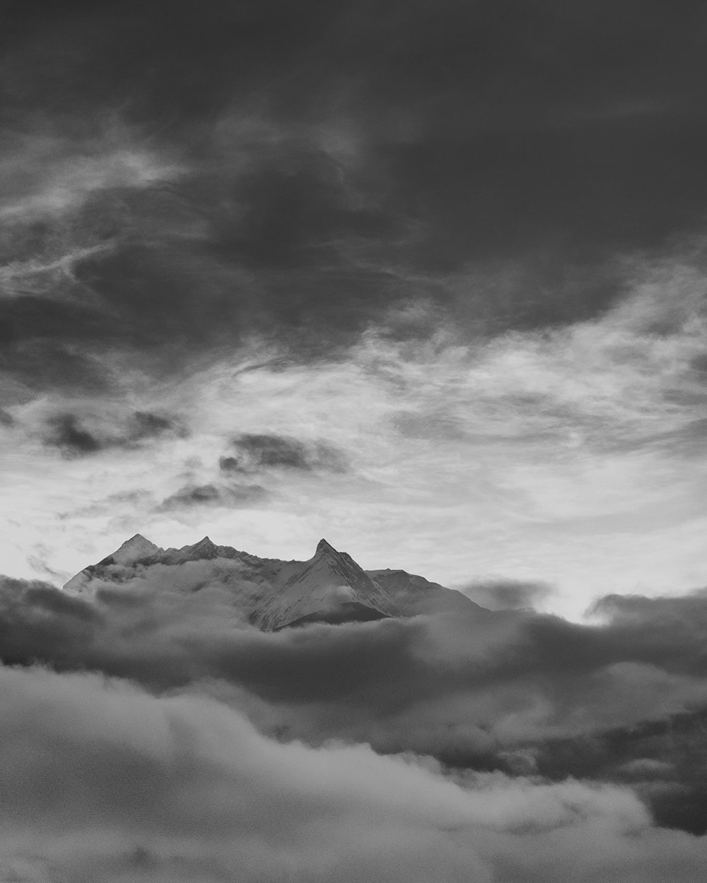 흐린 하늘 아래 산의 그레이스케일 사진
