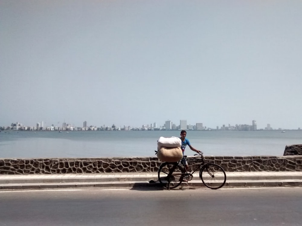 man in white shirt riding bicycle on gray concrete road during daytime