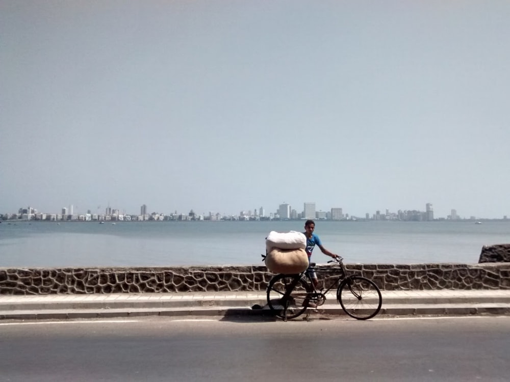 hombre en camisa blanca montando en bicicleta en carretera de hormigón gris durante el día