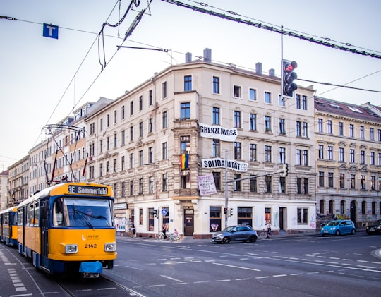 yellow and blue bus on road near brown concrete building during daytime in Leipzig Germany