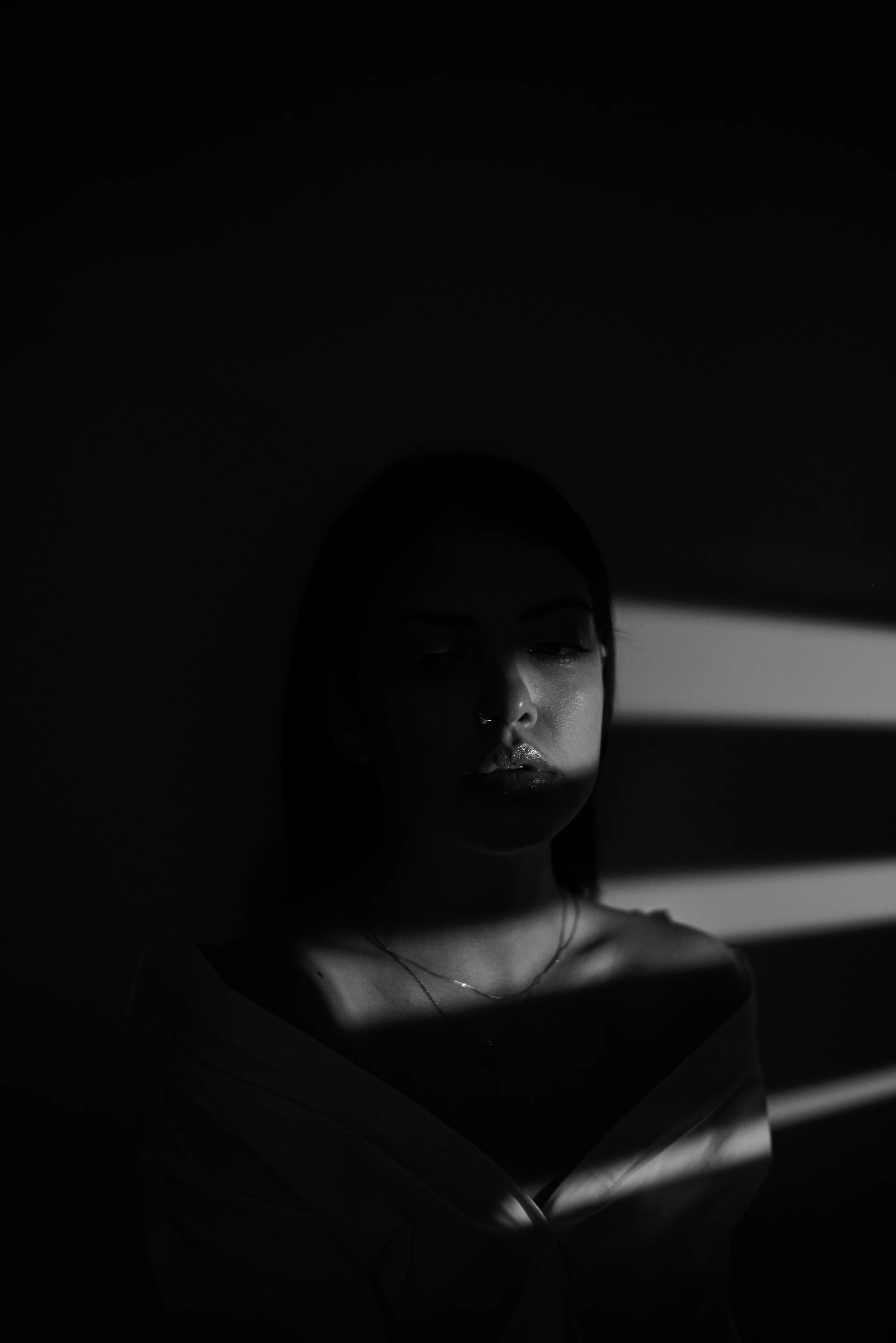 A moody film set illuminated by a single, warm spotlight casting dramatic shadows on the actor's face.