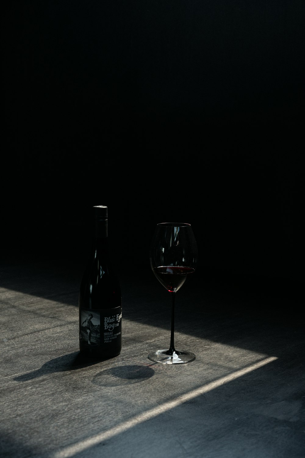 garrafa de vinho ao lado de copo de vinho na mesa