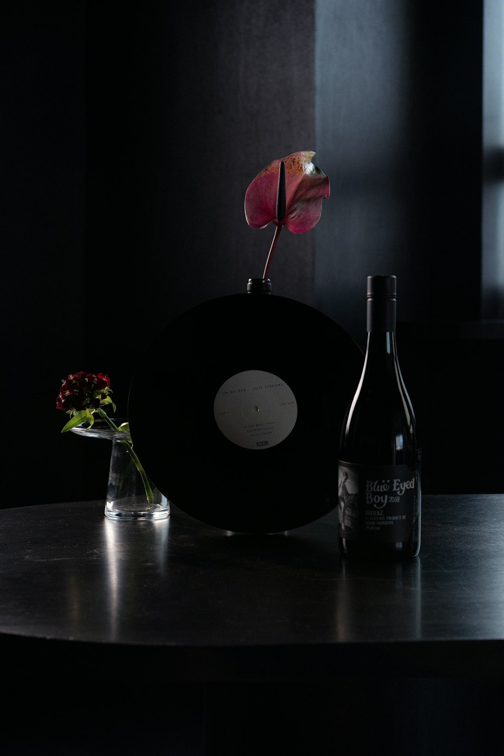 black wine bottle beside red rose