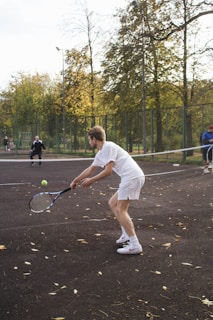 man in white t-shirt and white shorts holding tennis racket