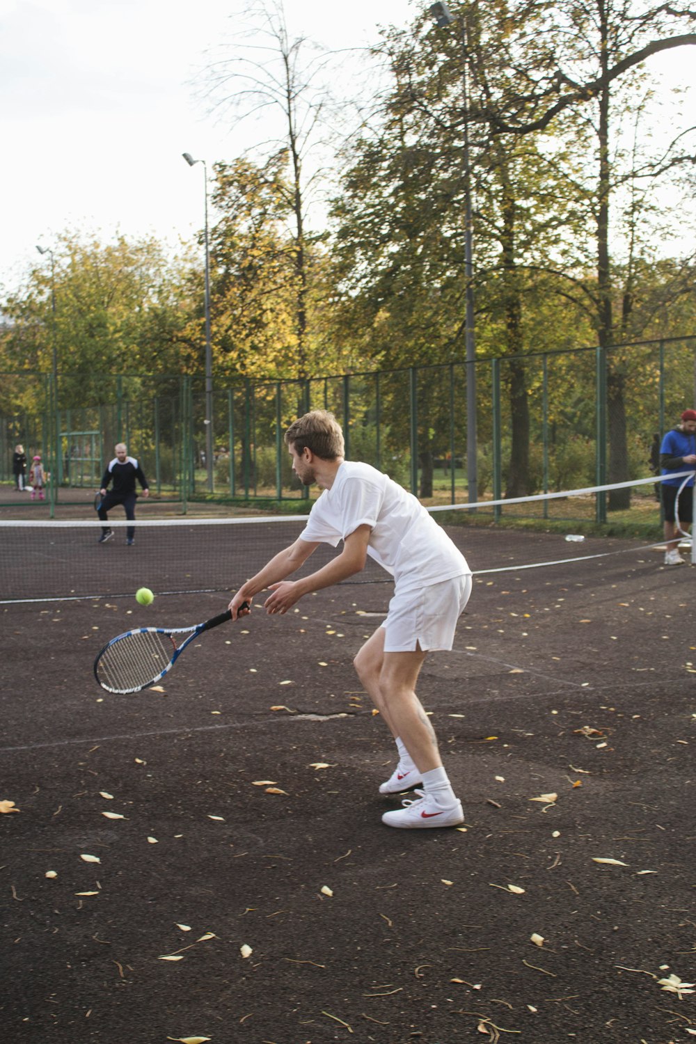 man in white t-shirt and white shorts holding tennis racket