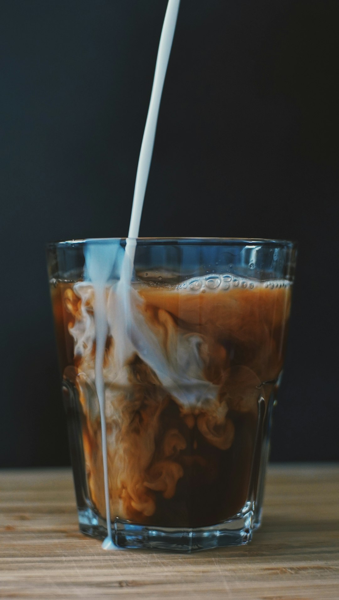 clear drinking glass with ice and brown liquid