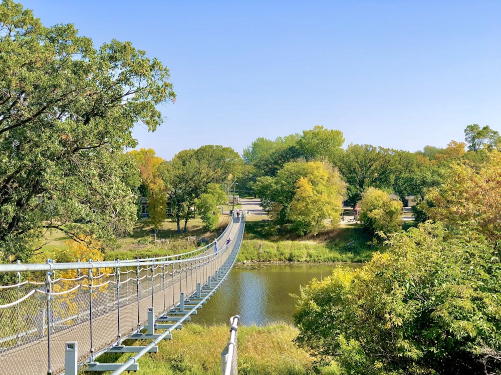 Weiße Brücke über den Fluss, tagsüber von grünen Bäumen umgeben