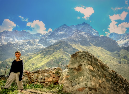 woman in black long sleeve shirt standing on rocky hill looking at mountains during daytime in Badrinath India