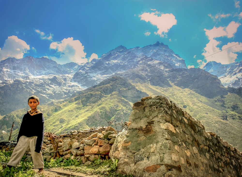 woman in black long sleeve shirt standing on rocky hill looking at mountains during daytime