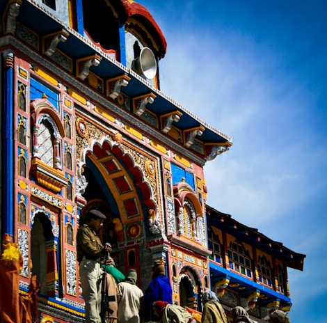 people walking near brown concrete building a group of people standing in front of Badrinath Temple