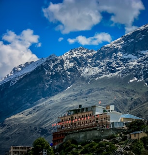 brown and white concrete building near snow covered mountain under blue sky during daytime