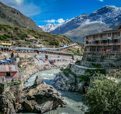 houses near river and mountain under blue sky during daytime