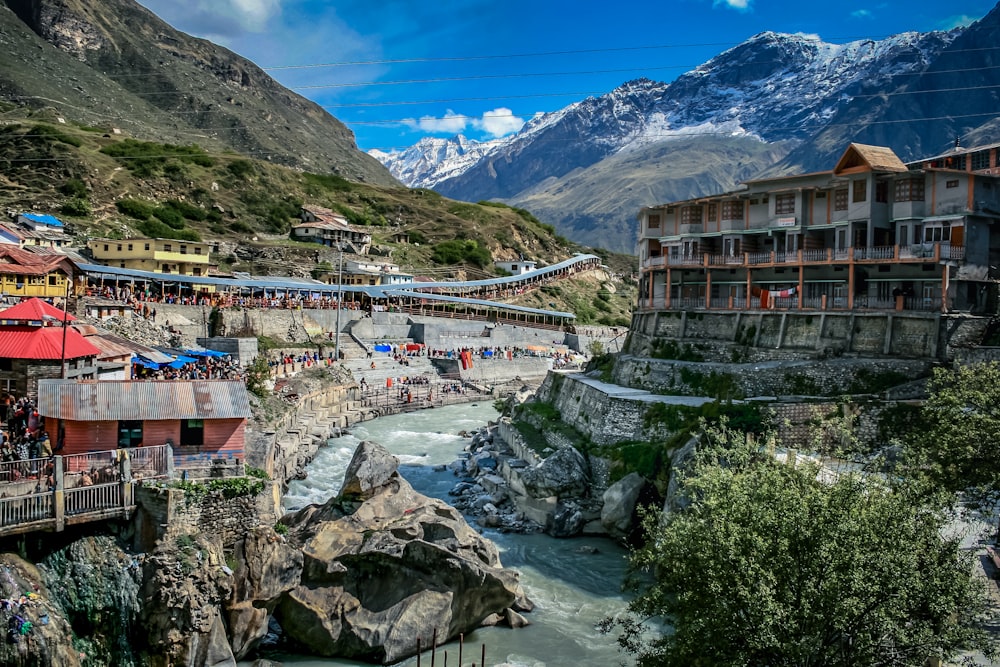 houses near river and mountain under blue sky during daytime