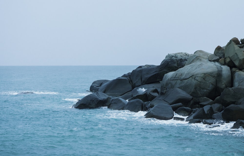 formação rochosa negra no mar durante o dia