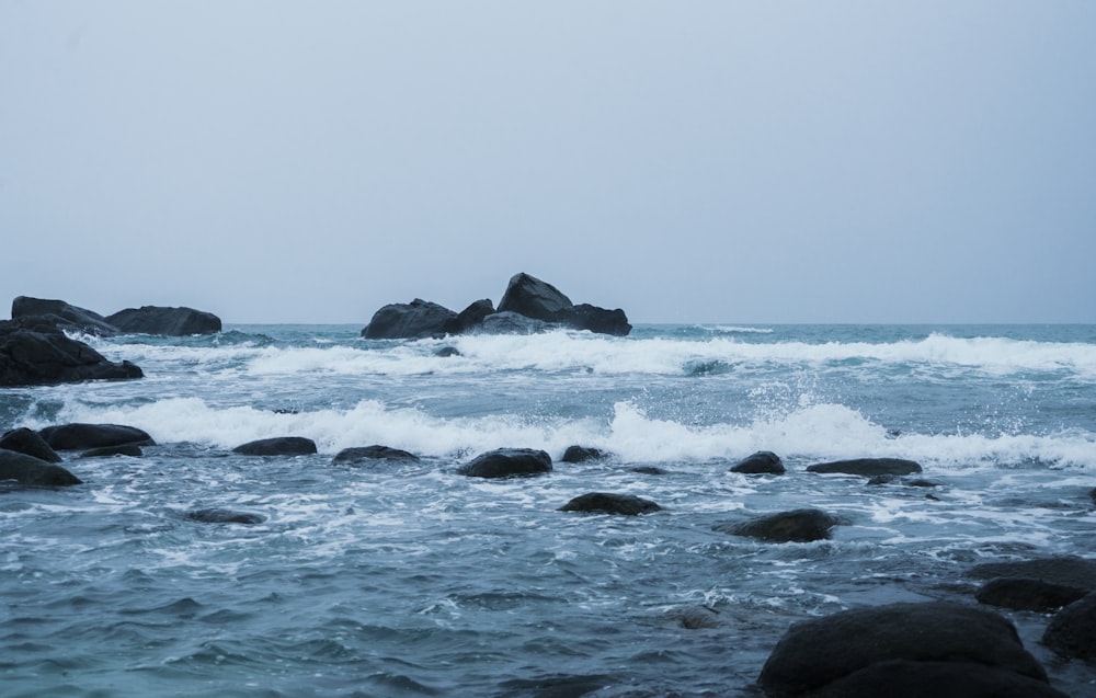 black rock formation on sea during daytime