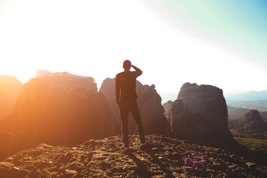 man in black jacket standing on white and black rock formation during daytime in Kalambaka Greece