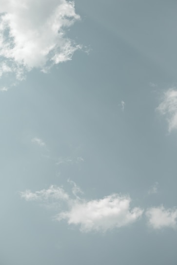 A serene abstract light blue background with soft sun rays filtering through clouds.