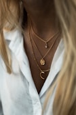 Model wearing layered silver necklaces that complement a casual outfit.