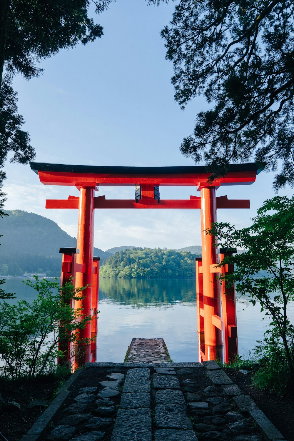 昼間の湖畔の赤い木のアーチ