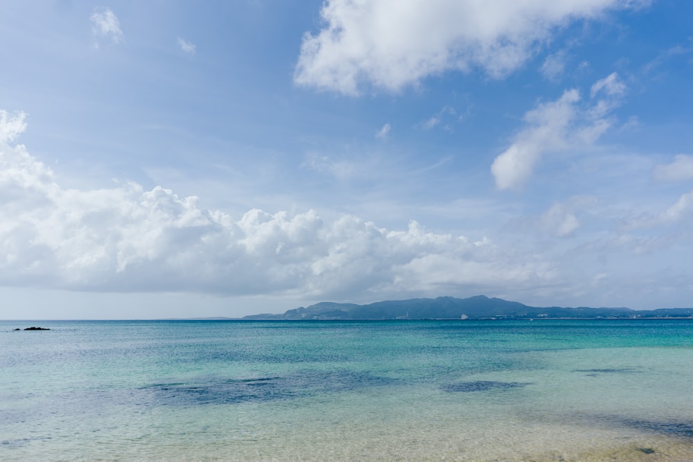 mar azul sob céu azul e nuvens brancas durante o dia