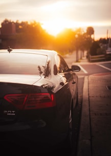 A sleek rental car parked on a city street at sunset.