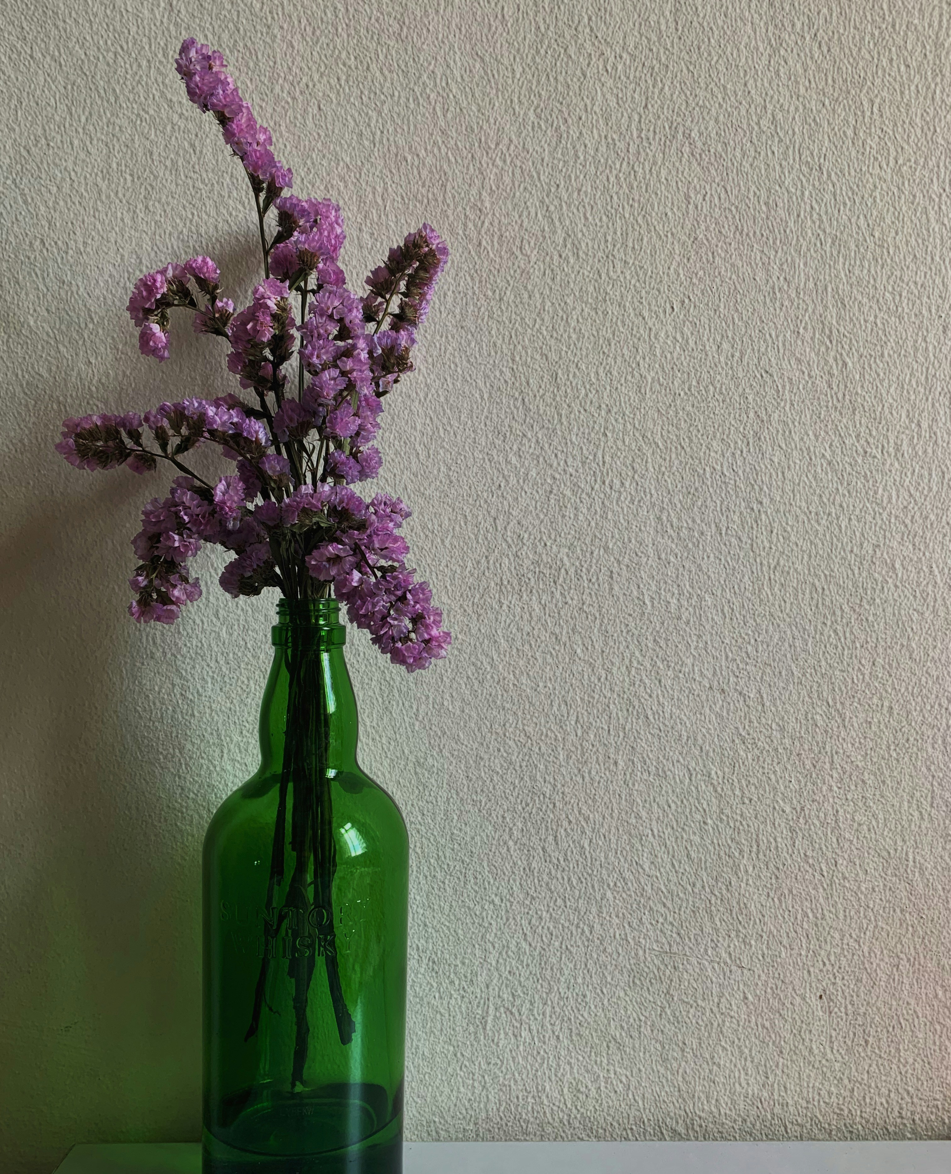 purple flowers in green glass vase