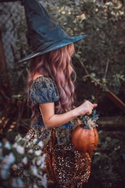 woman in black hat and brown dress holding pumpkin