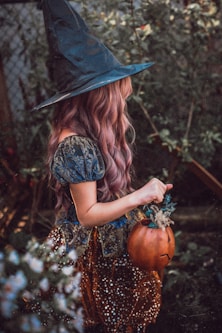 woman in black hat and brown dress holding pumpkin