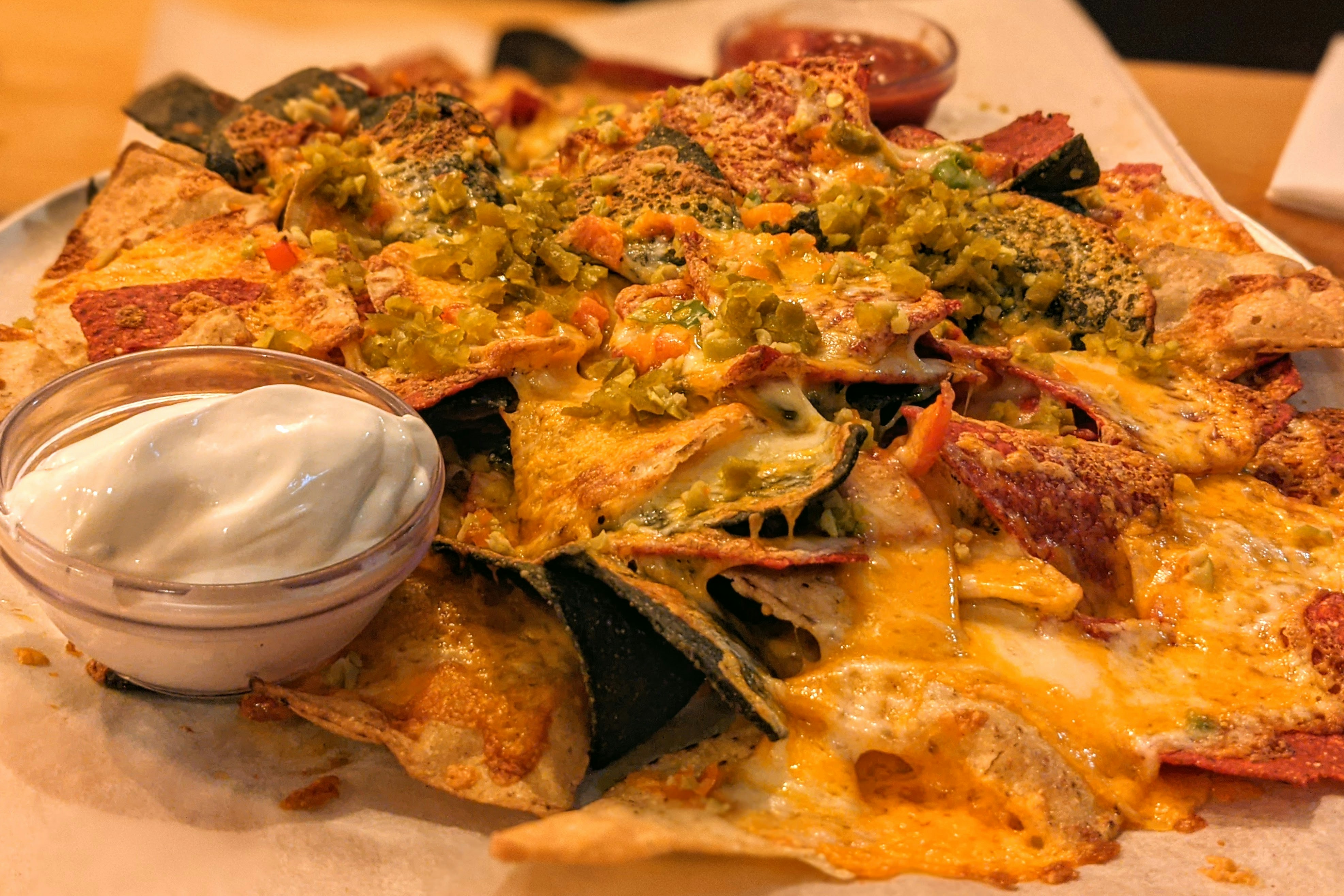 Thick-cut chips loaded with melted cheddar cheese sauce, jalapeños and spring onion in a paper cone