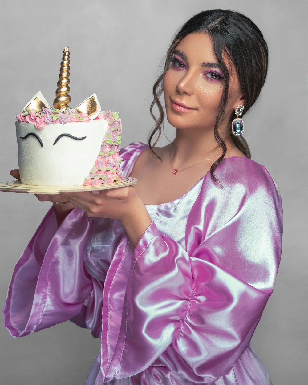Femme en robe fleurie rose et blanche tenant un gâteau blanc et or
