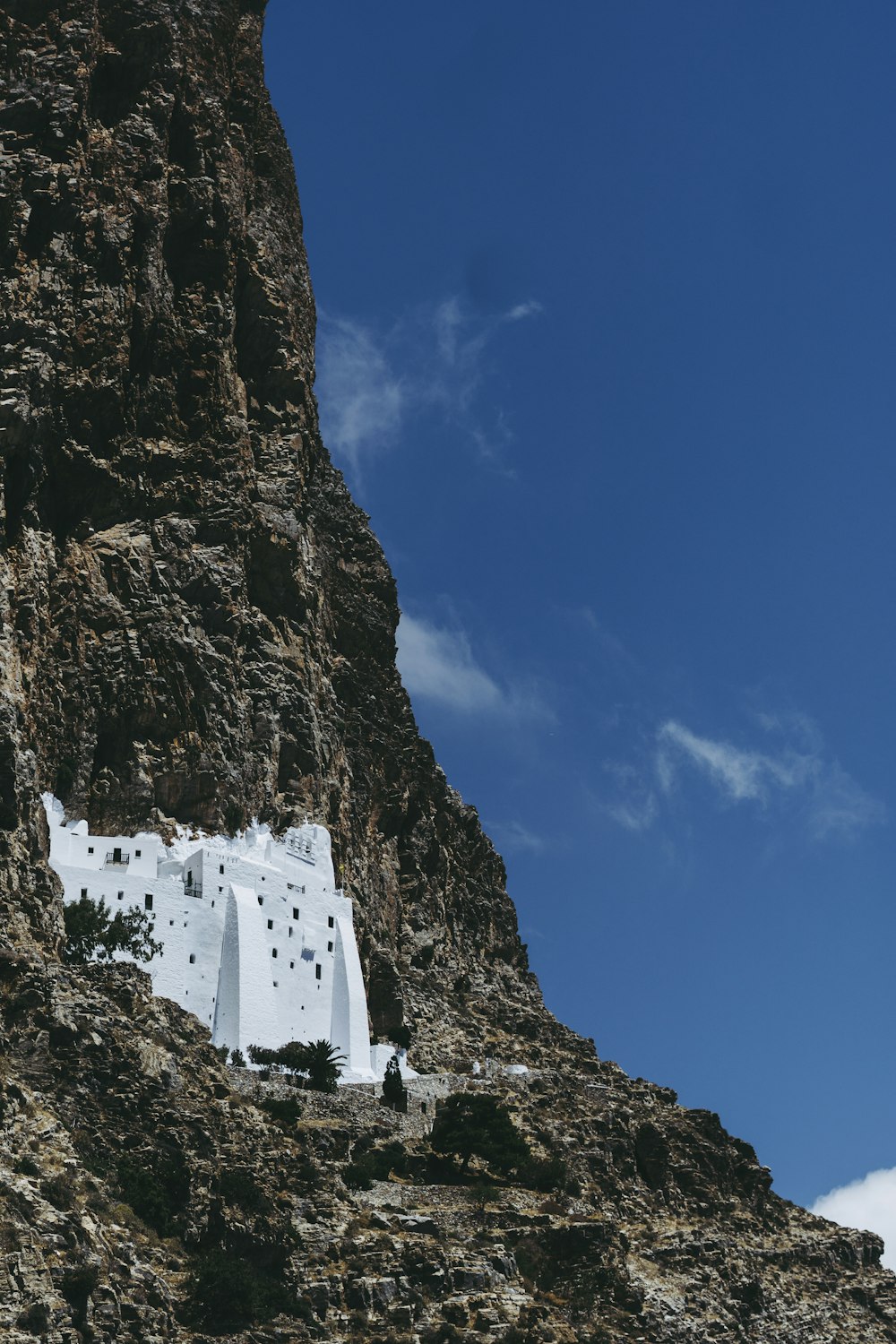 white concrete building on rocky mountain under blue sky during daytime