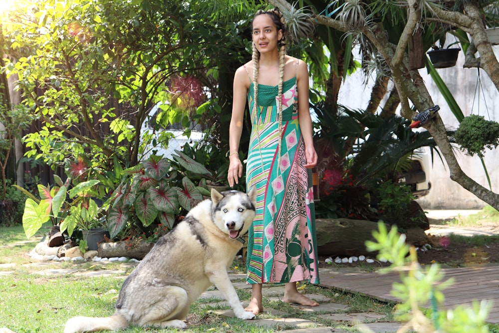 woman in white and red floral dress standing beside white and black siberian husky