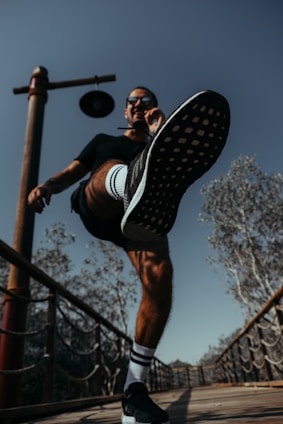 A dynamic photo of a male sports influencer filming content outdoors with vibrant cityscape in the background.