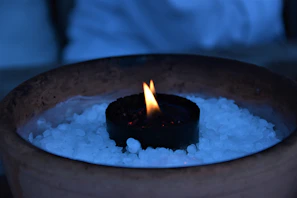A peaceful urn resting on a wooden shelf surrounded by soft candlelight