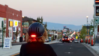 A cyclist adjusting a bright bike light on a city street at dusk.