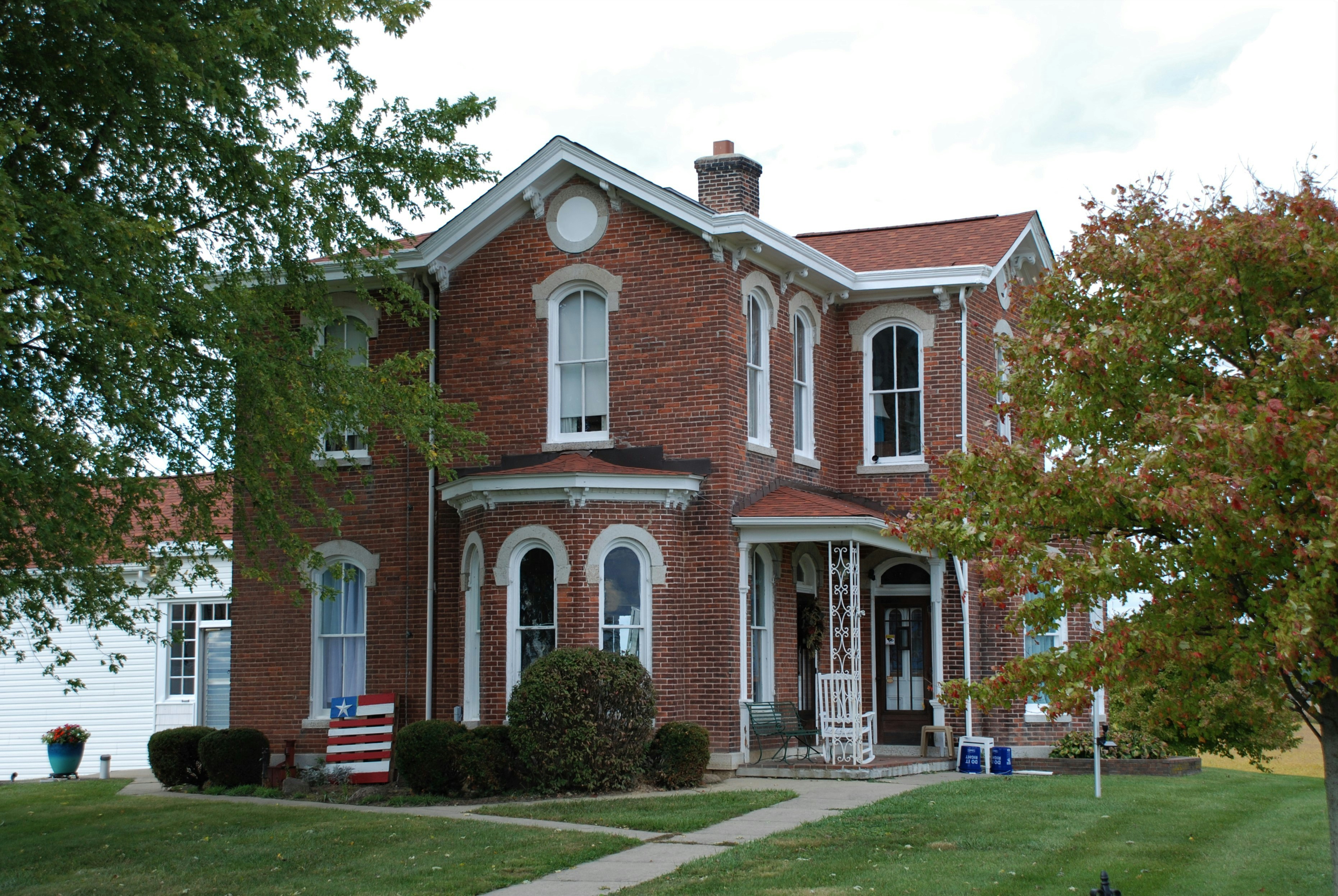 Traditional American home brick accents mature trees fall afternoon