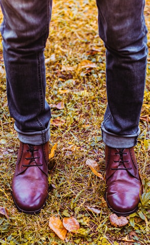 Casual boots worn by someone walking through a leafy park.