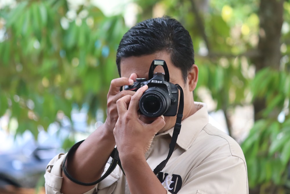 Hombre con camisa blanca sosteniendo una cámara DSLR Nikon negra